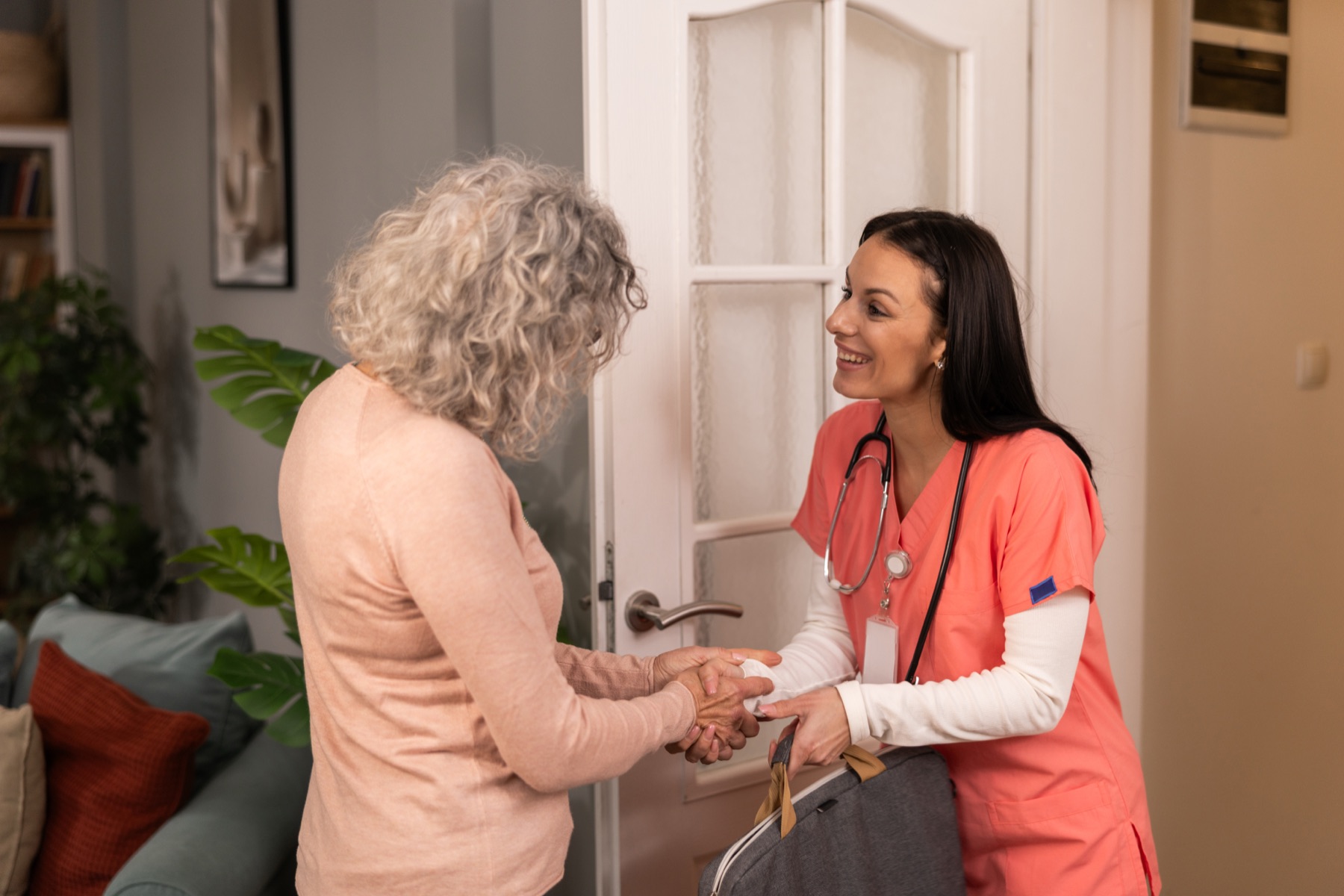 Home caregiver greeting a client at the front door